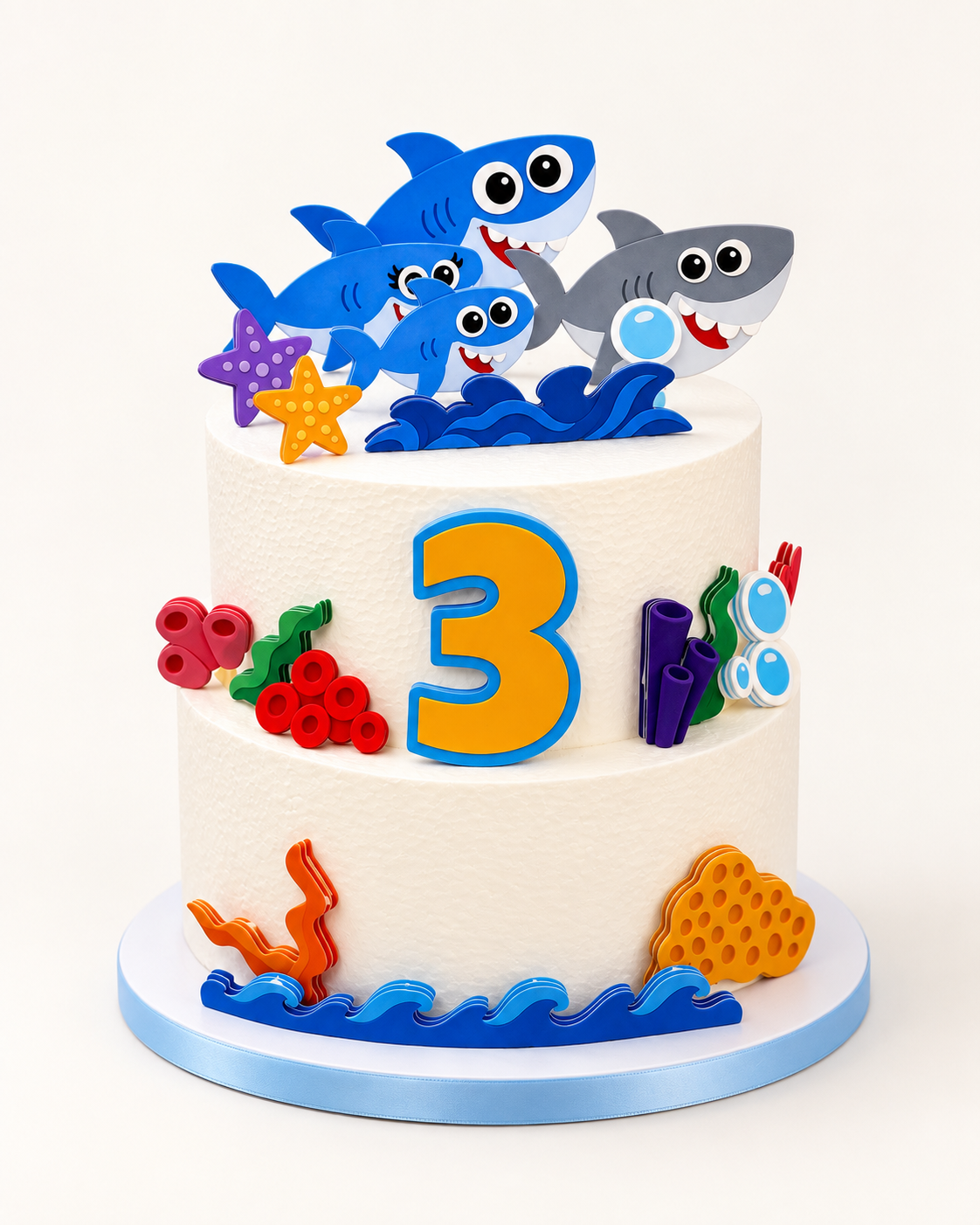 Shark cake decorations arranged on a white birthday cake with age 3