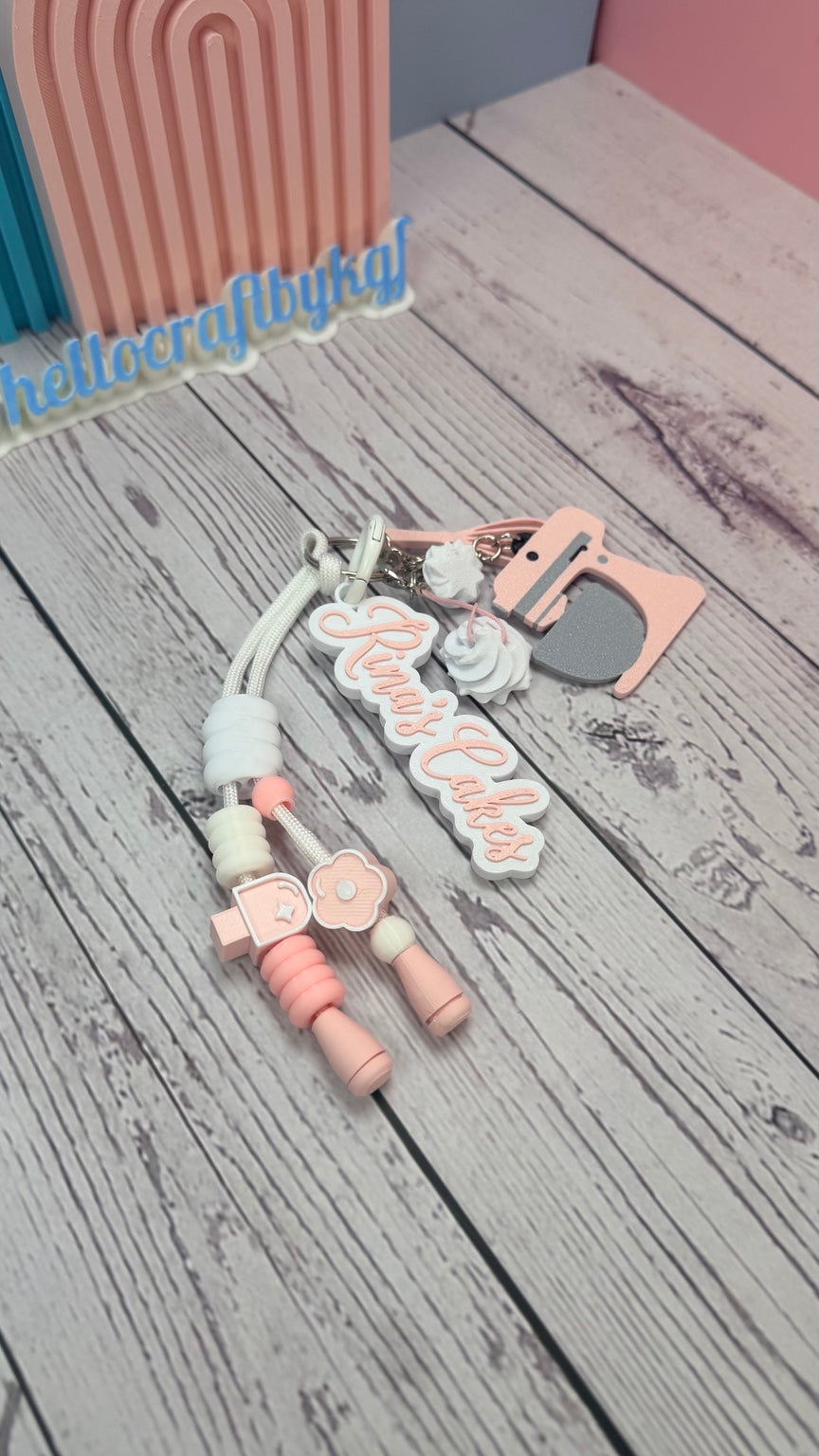 Angled view of personalized baker keychain with pastel pink mixer charm